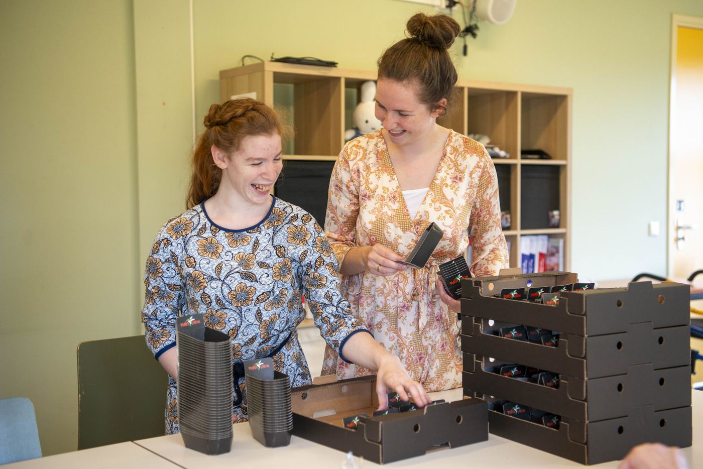 Twee jonge vrouwen pakken samen lachend dozen in